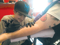 Jacob Randell & former teacher Chris Beauchamp at Aylmer’s 
Exotica Tattoo create a living monument – on the teacher’s forearm. Photo: SMC